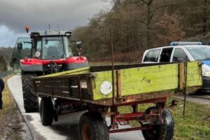 Traktor mit Anhänger auf B48, Öl auf Fahrbahn und Fahrradweg, Polizei vor Ort.