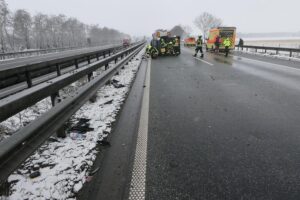 Unfallstelle auf Autobahn mit beschädigten Fahrzeugen und Einsatzkräften der Feuerwehr.