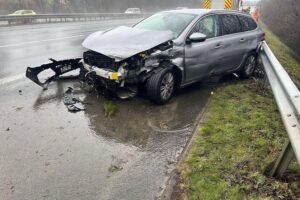 Unfall auf Autobahn A2: beschädigter Peugeot, Leitplanke, Regen, Polizei vor Ort.