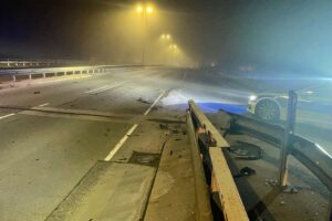 Unfallstelle mit beschädigter Schutzplanke und schwarzem BMW X5, polizeiliche Ermittlungen.
