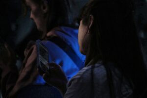 Junge Frau nutzt Smartphone, symbolisiert Cyberangriffe und Sicherheit in der digitalen Kommunikation.