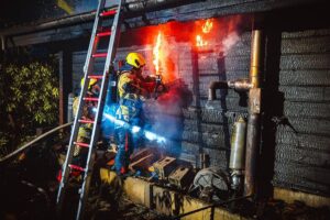 Vollbrand einer Saunahütte, Feuerwehr im Einsatz, Flammen und Rauch, dramatische Szenario.