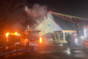 Brand von Fahrzeugen, Carport und Wohnhaus betroffen; Feuerwehr im Einsatz, keine Verletzten.