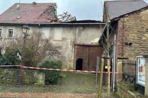 Eingestürztes Scheunendach, umgeben von Absperrungen, Feuerwehr und Technisches Hilfswerk vor Ort.