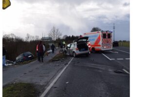 Verkehrsunfall mit Rettungsdiensten: beschädigte Autos, leicht verletzte Personen, gesperrte Straße, Einsatzkräfte.