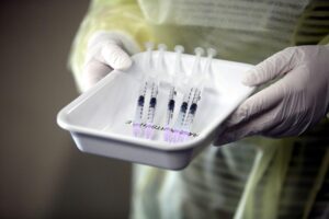 Zwei aufgezogene Impfspritzen, symbolisierend den neuen Kombinationsimpfstoff gegen Influenza und Covid-19.