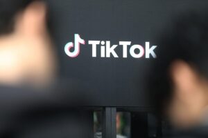 Tiktok-Logo mit Warnhinweis über süchtig machendes Design und EU-Kommissionsuntersuchung.