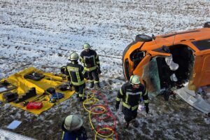 Unfallstelle mit umgekipptem Transporter, Feuerwehr bei der Rettung eingeklemmten Fahrers, Einsatzkräfte.