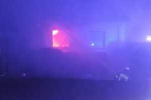 Feuerwehr löscht Brand in Einfamilienhaus, Flammen schlagen aus Fenstern, Bewohner unverletzt.