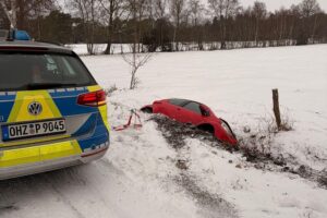 Winterliche Unfallstelle mit beschädigten Fahrzeugen und Räumfahrzeugen auf glatten Straßen.