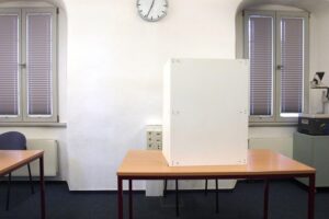 Wahllokal mit Wahlurnen und Briefwahlunterlagen, verdeutlicht Probleme der Bürgermeisterwahl.