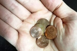 1- und 2-Cent-Münzen als Symbol für finanzielle Unsicherheit und politische Debatte um Gesundheitsabgaben.