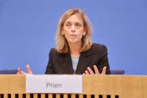 Karin Prien diskutiert über mögliche Bundespräsidentschaftskandidaturen, umgeben von politischen Symbolen.