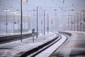 Winterlandschaft mit eingefrorenen Gleisen und beschäftigten Mitarbeitern der Deutschen Bahn bei Schnee.