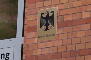 Bild könnte Menschen bei der Arbeit zeigen, verbunden mit Symbolen für Migration und Visum.