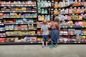 Kinder im Supermarkt wählen zuckerhaltige Getränke, was gesundheitliche Bedenken aufwirft.