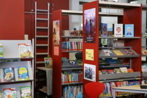 Kinder lesen in einer Schulbibliothek, umgeben von bunten Kinderbüchern und Lernmaterialien.