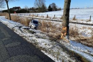 Ein schwer beschädigtes Auto, Baum, Graben – Unfallstelle mit winterlichen Straßenverhältnissen.