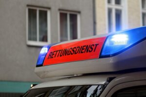 Rettungswagen und Polizeifahrzeuge an einer Unfallstelle, schwer beschädigtes Auto, verletzte Personen.
