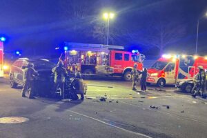 Verkehrsunfall mit zwei beschädigten Autos an belebter Kreuzung, Rettungsdienste im Einsatz.