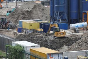 Baustelle mit Bauarbeitern, Maschinen und Materialien, symbolisiert Wachstum und Herausforderungen im Thüringer Bauwesen.