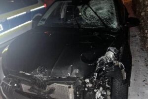 Ein schwer beschädigtes Auto, Verkehrsschilder und ein Trümmerfeld nach einem Unfall.