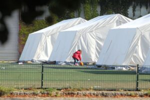 Flüchtlingskind in Zeltstadt, symbolisiert Herausforderungen und Hoffnungen für syrische Rückkehrer.