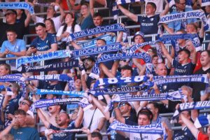 VfL Bochum-Fans jubeln, Oliver Olsen mit Rückennummer 13 auf dem Spielfeld.