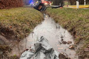 Schwerer Verkehrsunfall: brennendes Auto, Feuerwehr im Einsatz, überwiegend rauchige Umgebung, dramatische Szene.