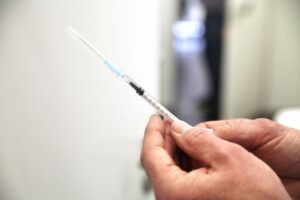Gerichtsurteil zur Impfstoffhaftung: Spritze und juristische Symbole symbolisieren Recht und Gesundheit.