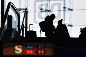 Reisende am Bahnhof symbolisieren die positive wirtschaftliche Entwicklung der Deutschen Bahn im Jahr 2025.