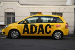 ADAC-Logo mit steigenden Mitgliedsbeiträgen und Mitgliedern, die besorgt diskutieren.
