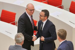 Zwei Männer diskutieren kritisch über die geplante rot-schwarze Landesregierung Brandenburgs.
