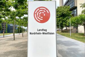 Landtagssitzung mit engagierten Abgeordneten, hitzige Diskussionen über Ministerin, politische Spannungen sichtbar.