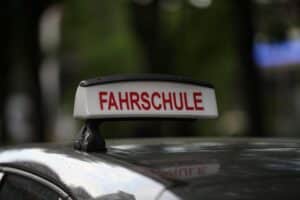 Fahrschule mit Schülern, Lehrern und Verkehrsschildern, symbolisiert bedenkliche Führerscheinreform und Verkehrssicherheit.