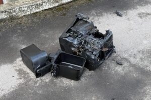 Feuerwehrleute löschen Zimmerbrand in Mehrparteienhaus, sichtbar Rauch und Brandsachen.