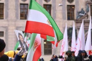 Protestierende Menschen mit Transparenten gegen den US-Militäreinsatz im Iran vor einem Regierungsgebäude.