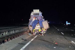 Feuerwehr im Einsatz: Atemschutztrupp an Unfallstelle mit beschädigtem Fahrzeug und Gasleck.