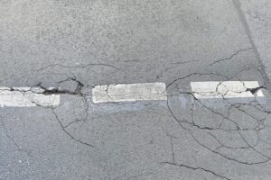 Rissige Fahrbahn und Schlaglöcher symbolisieren Frostschäden, die Hessens Straßen betreffen.