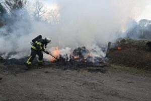 Heuballen auf Weide brennt, Feuerwehr im Einsatz gegen mutmaßliche Brandstiftung.