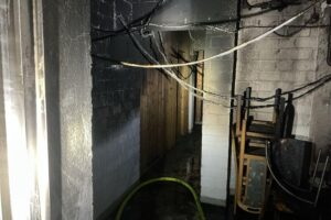Einsatzkräfte der Feuerwehr löschen Kellerbrand in Mehrfamilienhaus, Bewohner evakuiert.
