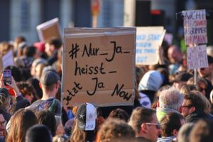 Demonstration gegen Gewalt an Frauen, mit Plakaten und Teilnehmern, die für Veränderungen eintreten.