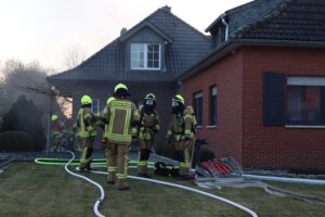 Einsatzkräfte löschen Küchenbrand in Einfamilienhaus; verletzter Bewohner wird medizinisch versorgt.