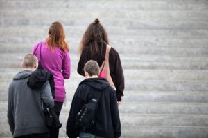 Vier junge Menschen auf einer Treppe, symbolisieren unterschiedliche Berufschancen und Lohngleichheit.