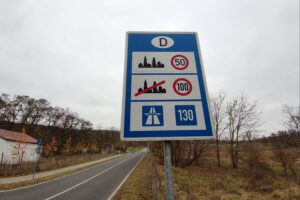 Ein deutscher Straßenabschnitt mit Tempolimit-Schild vor einer urbanen Kulisse, um Energieeinsparung anzuzeigen.