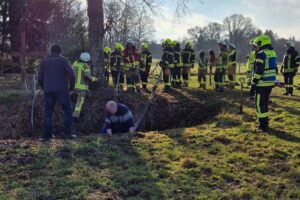 Pony-Rettung durch Feuerwehr aus Graben, Einsatzkräfte arbeiten gemeinsam, Tierarzt überwacht Zustand.