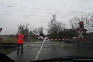 Beschädigte Bahnschranke am Bahnübergang, Polizei sucht flüchtigen Fahrer, Sicherheitsmaßnahmen ergriffen.
