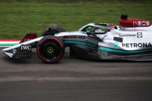 George Russell jubelt auf dem Podium, umgeben von Teamkollegen und der Formel-1-Trophäe.