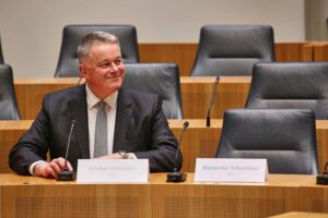 Gordon Schnieder sitzt neben einem leeren Stuhl, symbolisiert politische Niederlage der SPD.