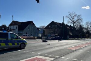 Unfallstelle mit beschädigten Fahrzeugen und Polizeipräsenz nach schwerem Motorradunfall in Bielefeld.